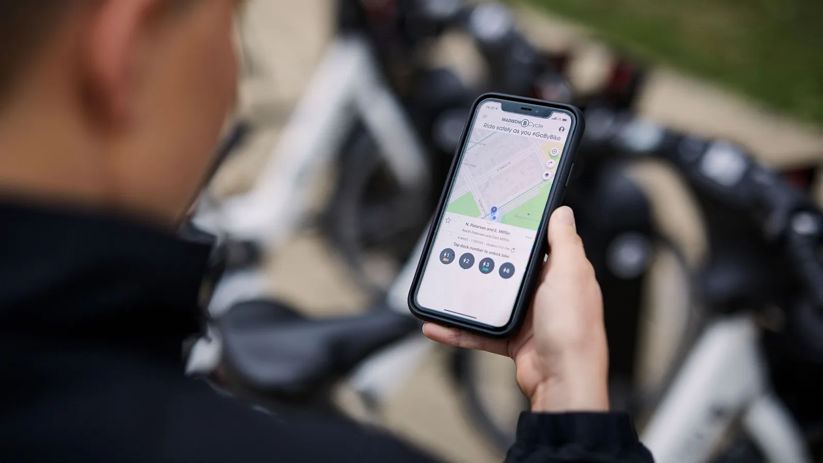 Woman using the BCycle app on her iphone in front of a bike share station.