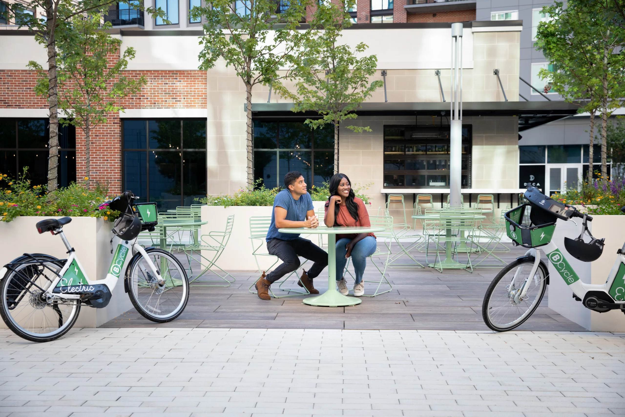 Couple sitting at outdoor table deciding where to ride their bike share bicycles