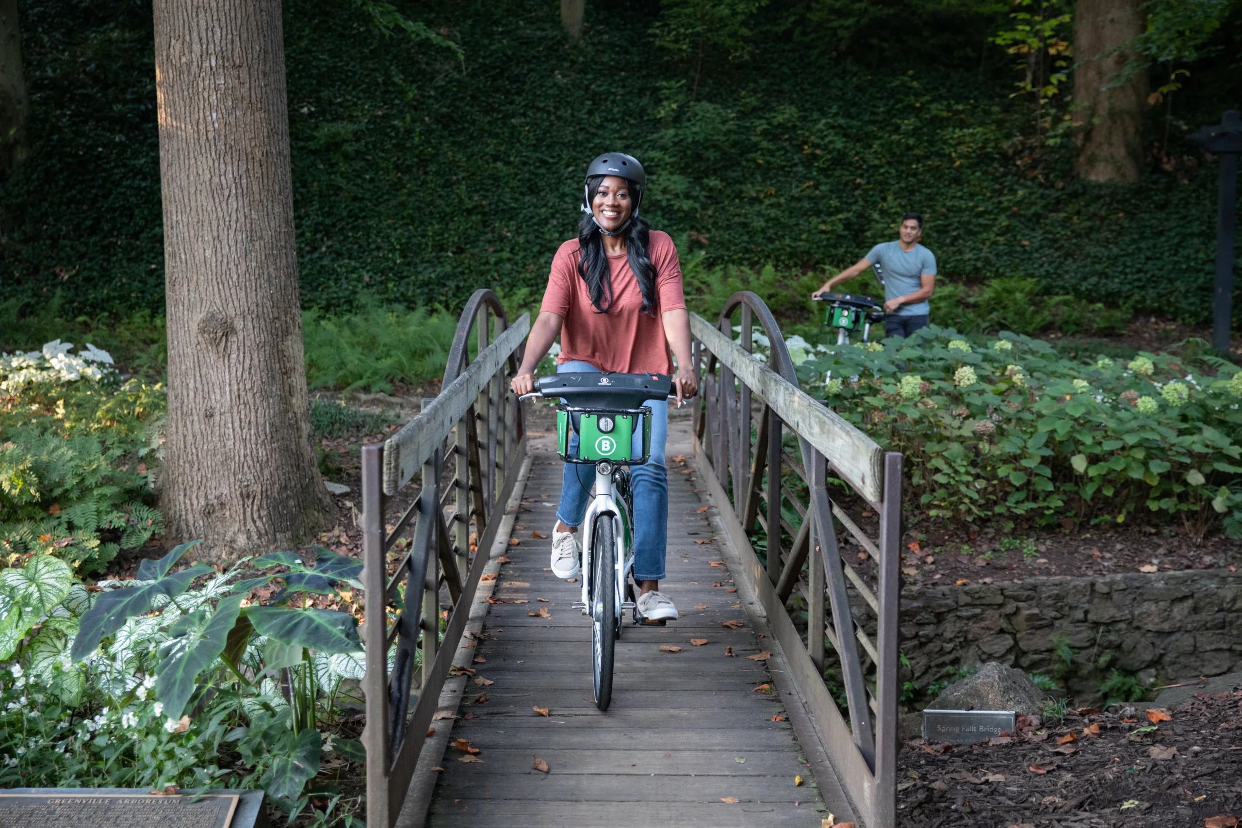 Woman riding a bike share bicycle across wooden bridge on the Swamp Rabbit Trail