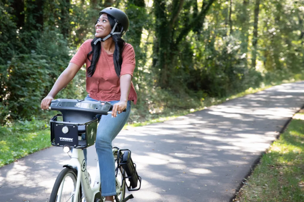 Black woman riding a bike share bicycle on the Swamp Rabbit Trail.
