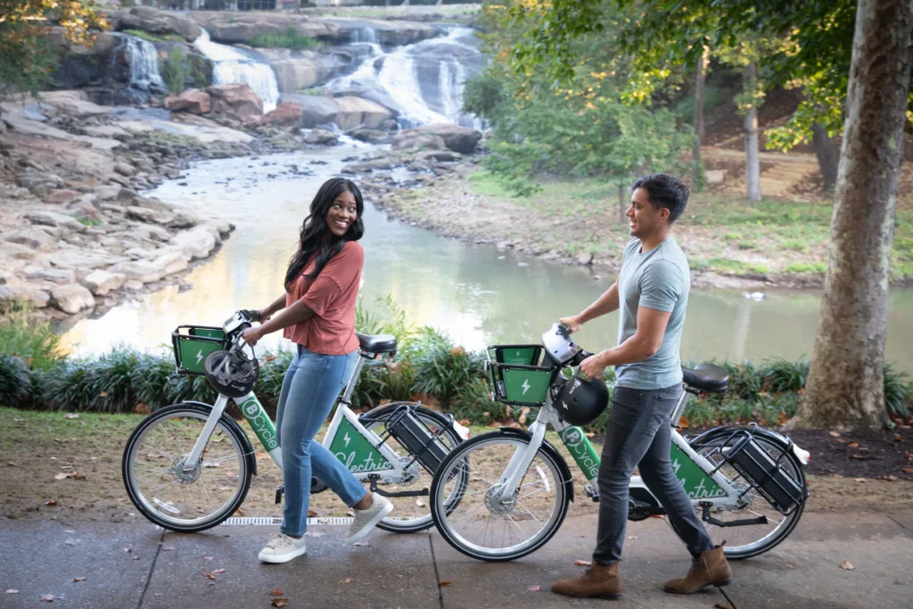 Two people walking their bike share bikes on the Swamp Rabbit Trail.